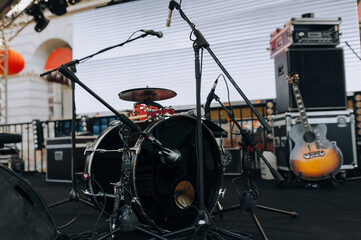 Fototapeta na wymiar Scene with black drum kit, microphone and guitar. Outdoor music club. Lviv, Ukraine