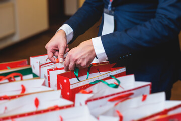 Naklejka premium New Year corporate gifts and souvenirs for company employees, Christmas party surprise gift bag, gift giving at office work, red green and white paper bags, presents exchange with colleagues at work