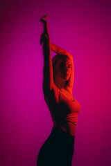 A fit woman in a dynamic pose, her figure outlined by a striking magenta light