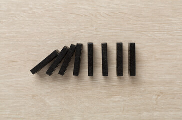 Black domino tiles on wooden background, top view
