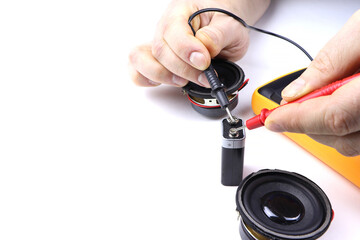 An electrician measures the capacity of a battery with an electronic multimeter. Measuring instruments. Voltage measuring tool. Checking battery voltage. Mans hands testing battery voltage.