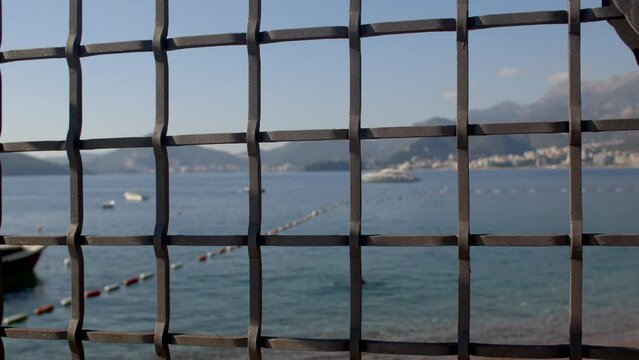 Sea and beach behind a metal grille. Desire for Freedom concept. Scene may evoke a longing for freedom, with the sea and beach serving as a metaphor for unattainable or restricted aspirations.