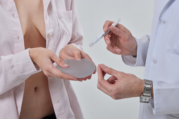 Professional plastic surgeon showing silicone breast implants to his female patient, mastopexy...