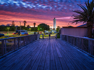 Wooden bridge leading to the Milnerton Lighthouse during a colourful sky sunset, Cape Town, South...