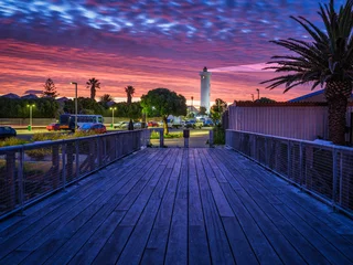 Papier peint adhésif Montagne de la Table Wooden bridge leading to the Milnerton Lighthouse during a colourful sky sunset, Cape Town, South Africa