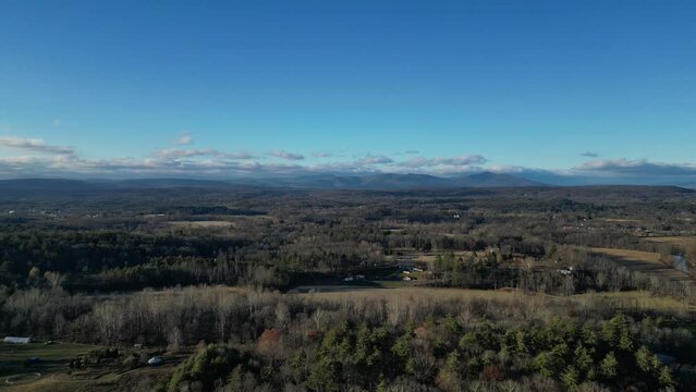 aerial footage of small rural town with distant mountains (fly forward, drone, from above) nature, trees, woods, usa countryside, catskills, hills, distance, panorama, flying, approaching