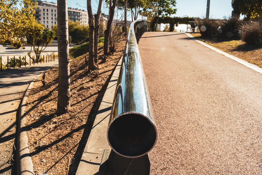 Una toma creativa centrada en un pasamanos met&aacute;lico brillante, capturando la perspectiva y reflejos bajo la luz del sol en un entorno urbano. Ideal para destacar la relaci&oacute;n entre dise&ntilde;o y funcionalid