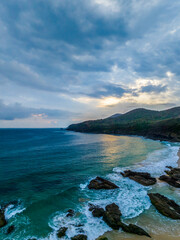 Fototapeta premium Rain clouds, rocks and sunrise at the seaside