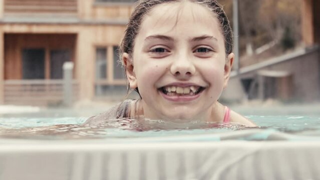 Young girl playing and swimming in an outdoor pool in winter.