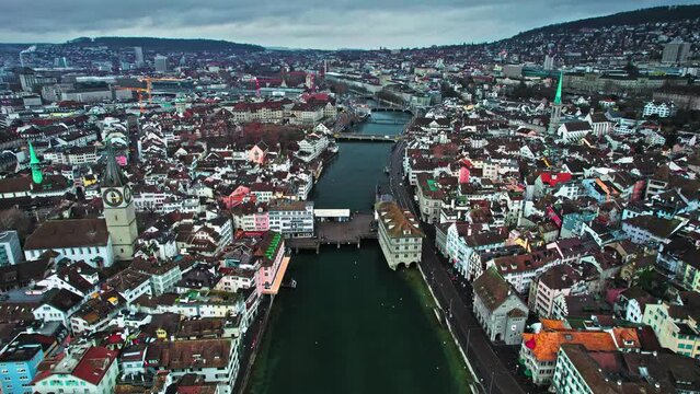 Aerial view of colourful houses, banks and finance buildings in Zurich. Panoramic view of the turquoise lake and bridge, Iconic twin-towered Romanesque Grossm&uuml;nster cathedral and historical Lindenhof.