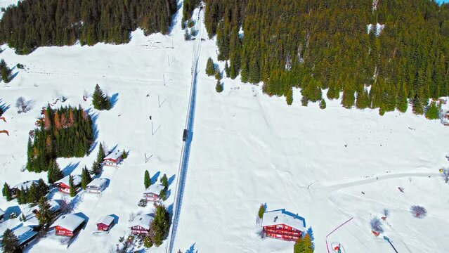 Aerial view of the Alps covered with snow and an electric train taking tourists to a car-free resort in Murren. Alpine Swiss mountain during winter at Lauterbrunnen Valley.
