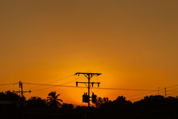 Silhouette of high voltage electric pole at sunset sky background.