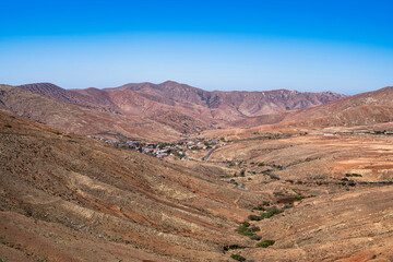 A small town is seen in the desert valley. Photography taken in Fuerteventura, Canary Islands, Spain.