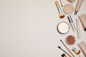 Face powders and other makeup products on beige background, flat lay. Space for text