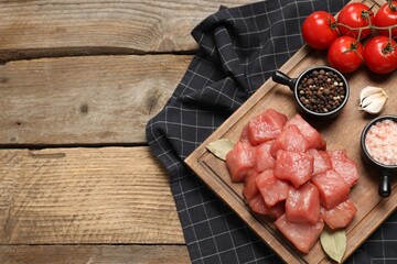 Raw beef meat and different ingredients for cooking delicious goulash on wooden table, flat lay. Space for text