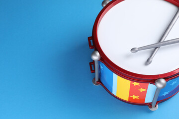 Colorful drum and sticks on light blue background, space for text. Percussion musical instrument