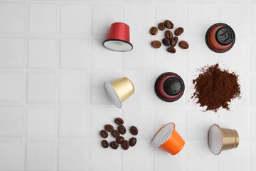 Foto auf Acrylglas Kaffee Bar Many coffee capsules, powder and beans on white tiled table, flat lay. Space for text