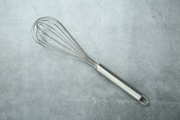 Metal whisk on gray table, top view