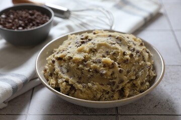 Chocolate chip cookie dough in bowl on tiled table, closeup