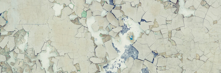 Peeling paint on the wall. Panorama of a concrete wall with old cracked flaking paint. Weathered rough painted surface with patterns of cracks and peeling. Wide panoramic texture for grunge background