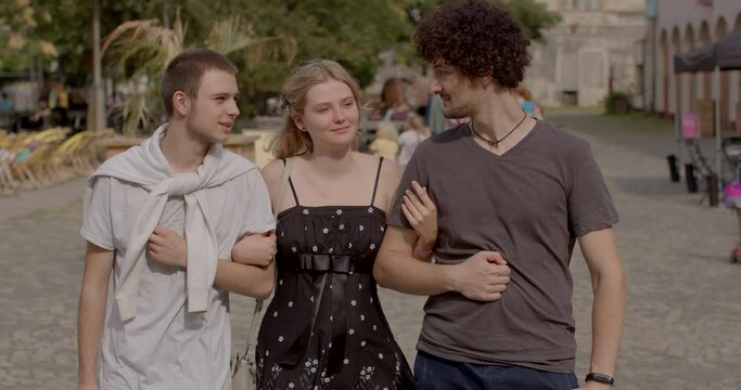 Romantic relationships among three individuals polyamory, involve consensually and openly loving and connecting with multiple partners simultaneously. Girl and two guys posing looking at camera. 