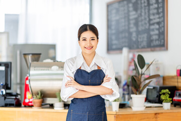 Opening a small business, AHappy Asian woman in an apron standing near a bar counter coffee shop,...
