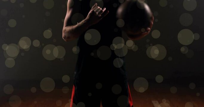 Animation of caucasian basketball player throwing ball and spots of light on black background