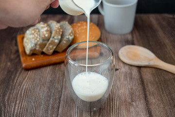Breakfast set Male hands pouring milk onto glasses and slices of bread.