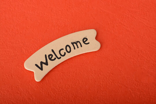 Wooden label with text WELCOME on a red background.