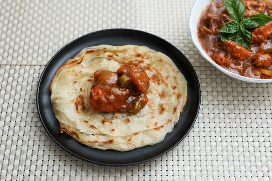Chilly chicken with Kerala parathas porotta roti parotta barotta naan layered flatbread made from maida whole wheat flour. Eat with spicy Asian chicken beef egg curry gravy. Indian food.