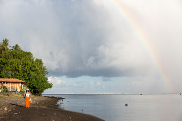 A colorful rainbow over the ocean waves at sunset in Tahiti 