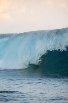 Blue and golden waves on the ocean at sunset in Tahiti ready for surfer