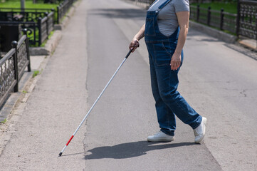 Blind pregnant woman crosses the street with the help of a tactile cane.