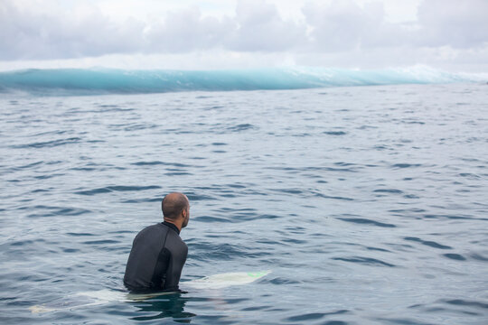 A man waits for a wave in the ocean in Tahiti surfing