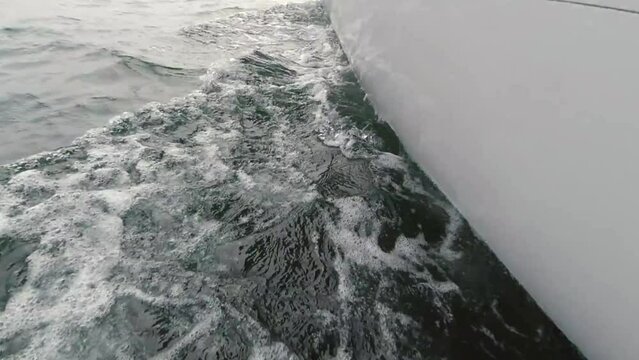 View from the deck of the yacht to the bow, close-up. Side view of the green sea and waves. Concept, lifestyle and freedom. Slow motion