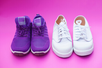 Two  pairs of  white and puple canvas sneakers on pink backgrond. Comfortable, fashionable. Concept, shoes for doing sport or exercise also can wear for traveling, hiking.        