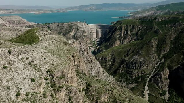 A huge dam shot from a distance. Aerial photography of a mountain landscape, a river and a reservoir. Shooting at high altitudes.