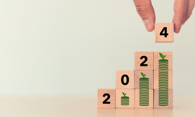 Financial growth concept in 2024. Close up hand arranging wooden cubes stacking  2024 standing on...