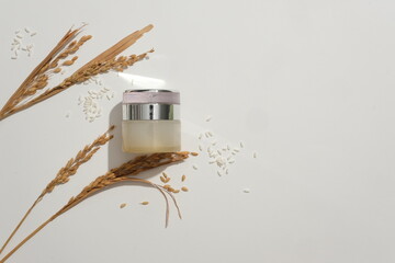 A lotion jar with a luxurious design that stands out on a white background with whole grain rice....
