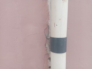 White pvc pipe clamped on a faded pink wall. suitable for texture and background themes.