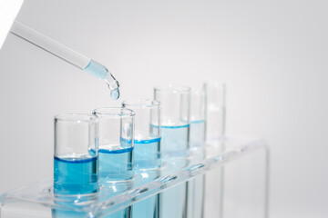 Chemistry laboratory tube glass, science laboratory research and development concept, flask, beaker, and test tubes with dropping blue liquid water sample test, scientific test tubes equipment.
