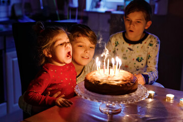 Adorable kid boy celebrating tenth birthday. Baby sister child and two kids boys brothers blowing...