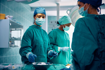 Group of female doctors performing surgical procedure in operating room. - obrazy, fototapety, plakaty
