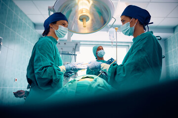 Female surgeons cooperating during surgery in operating room.