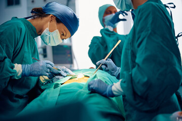 Female surgeon making incision with scalpel in operating room. - obrazy, fototapety, plakaty