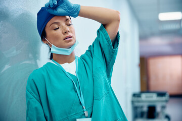 Female surgeon feeling tired after surgical procedure in hospital.