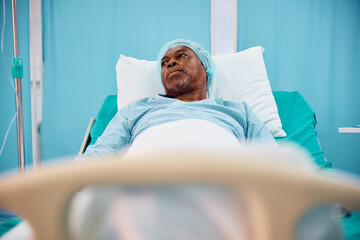 Pensive black senior man waiting for surgery in hospital ward.