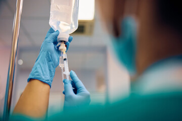 Close up of nurse injecting medicine in patient's IV drip.