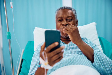 Happy African American senior patient making video call while recovering in hospital.