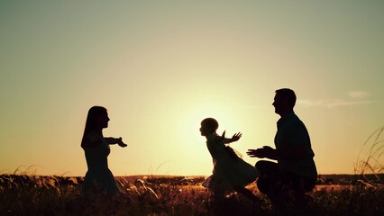 Family plays with daughter running to hugs of parents as sun sets behind rolling field